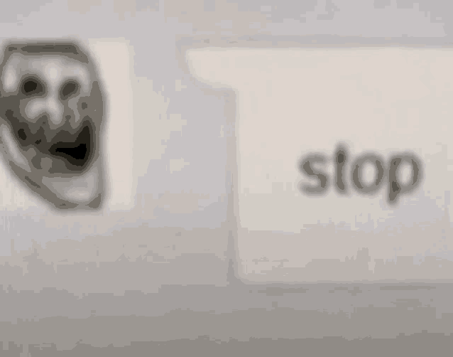 a blurred image of a troll face next to a stop sign .