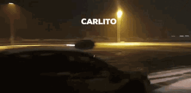 a car is driving down a street at night and the word carlito is on the bottom of the screen