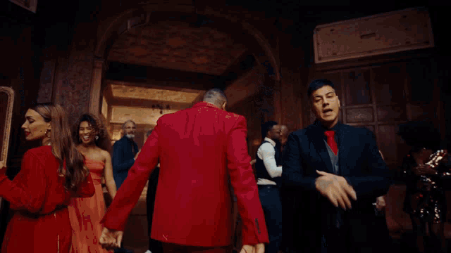 a man in a red tuxedo and a man in a black suit are standing in a room
