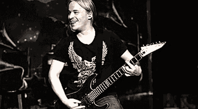 a man in a black shirt is playing a guitar