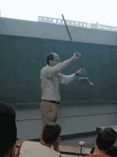 a man in a white shirt is holding a snake in front of a group of people