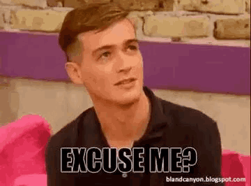 a man is sitting on a pink couch with the words `` excuse me '' written on his face .