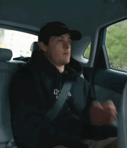 a man is sitting in the back seat of a car holding a can of soda