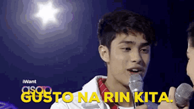 a young man singing into a microphone with gusto na rin kita