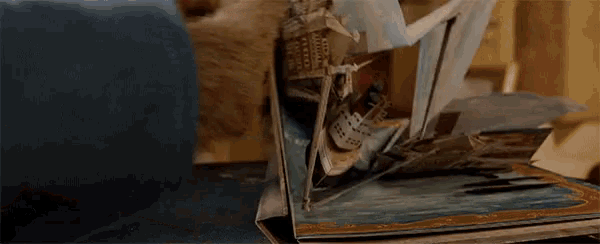 a person is holding an open book with a ship in it