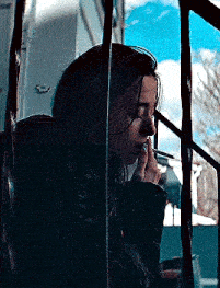a woman is smoking a cigarette in front of a window behind bars .