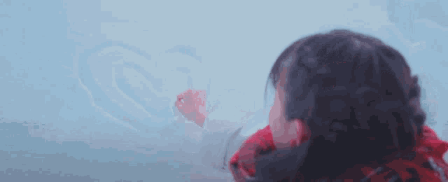 a girl wearing a red scarf is holding her hands in the snow