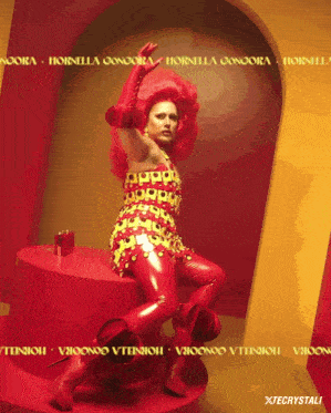 a woman in a red and yellow outfit is sitting on a red pedestal