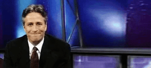 a man in a suit and tie is making a funny face in front of a television .
