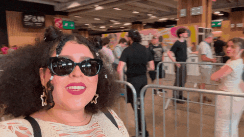 a woman wearing sunglasses is smiling in front of a sign that says s & m