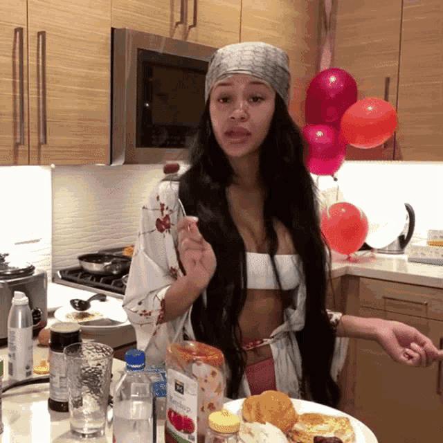 a woman is standing in a kitchen with a plate of food and a bottle of apple juice