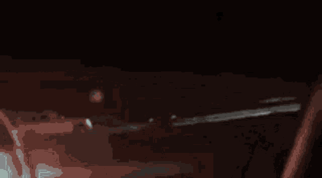 a car is driving down a highway at night with smoke coming out of the hood .