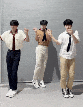 three young men are dancing in front of a wall .