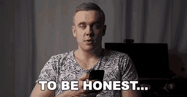 a man holding a cell phone with the words to be honest behind him