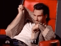 a man is sitting in a red chair with his arms outstretched and holding a remote control .
