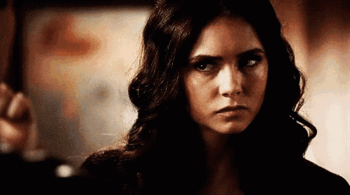 a woman with long dark hair is looking at the camera and making a serious face .