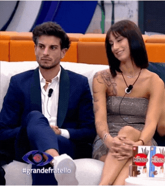a man and a woman are sitting on a couch with the words grandefratello on the bottom