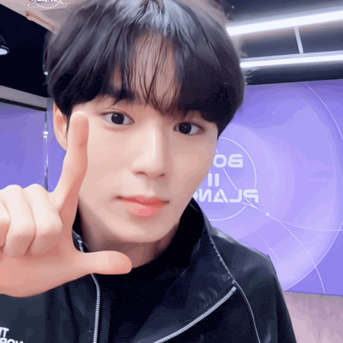 a young man giving a thumbs up in front of a purple background that says 06