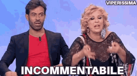 a man and a woman are standing next to each other and the woman is saying incommentable