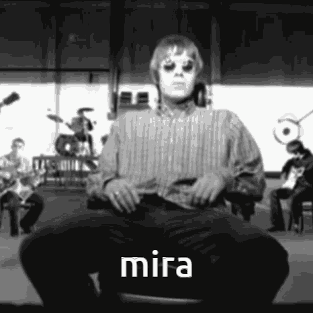a man in a striped shirt is sitting on a chair with the word mira below him