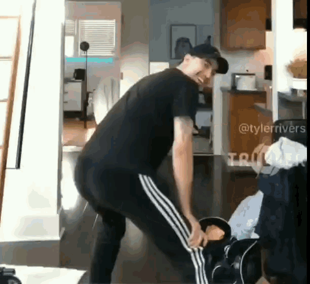 a man in a black shirt and white striped pants is squatting on a wooden floor .