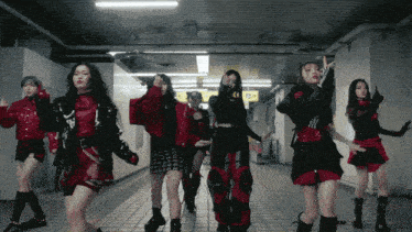 a group of women are dancing in a hallway with a yellow sign that says exit