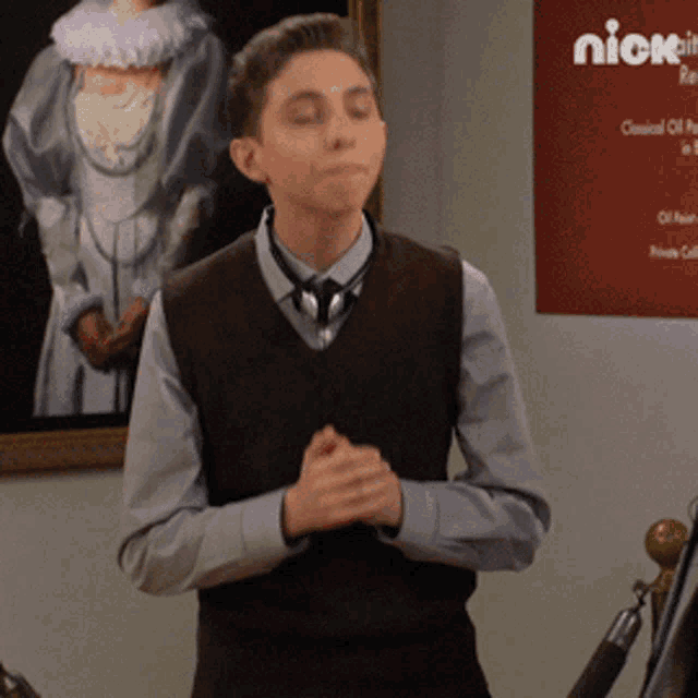 a young man stands in front of a poster that says nick