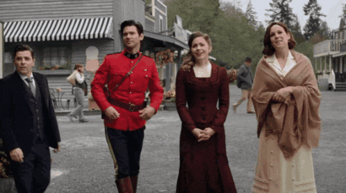 a man in a red uniform walks with two women