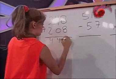 a girl in a red shirt is writing on a white board with math problems on it