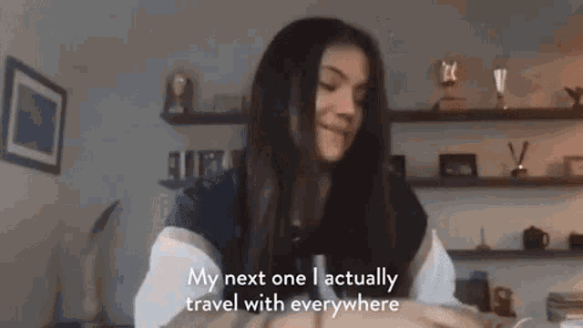 a woman is standing in a room with a microphone in her hand and talking about her next trip .