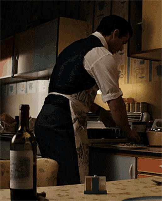 a bottle of wine sits on a table next to a man