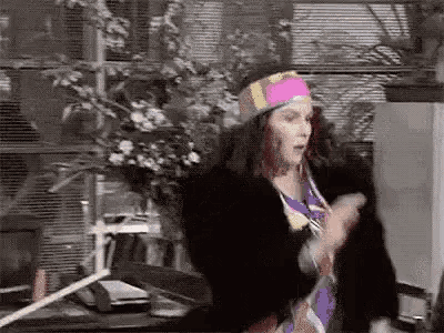a woman in a colorful headband is standing in front of a desk in an office .