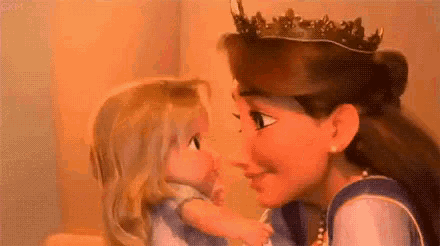 a woman wearing a crown is holding a baby doll and kissing it .