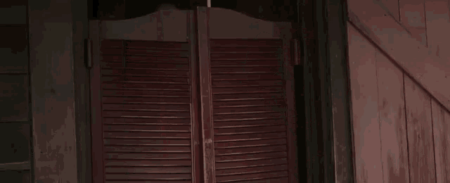 a woman is standing in a doorway waving her hand and smiling .