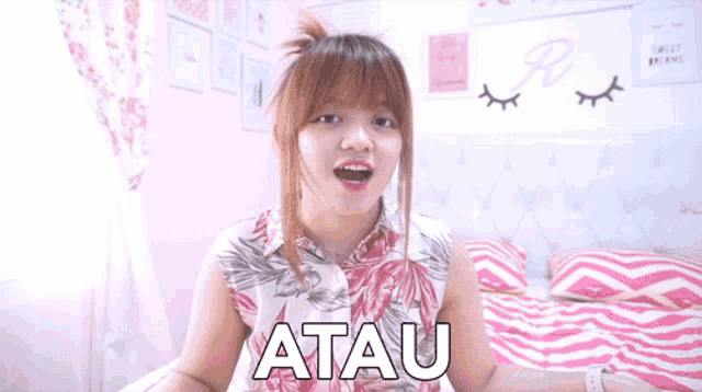 a girl sitting on a bed with the word atau written on her chest