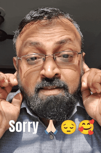 a man with glasses and a beard holds his hands to his ears with the word sorry below him