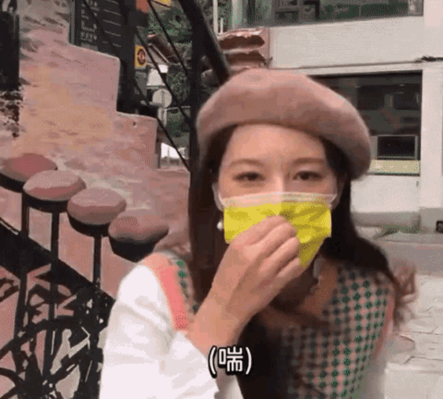 a woman wearing a beret and a yellow mask covering her mouth