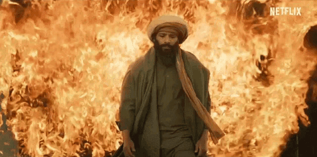 a man is standing in front of a large fire .