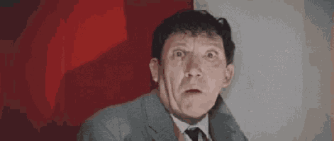 a man in a suit and tie is making a funny face .