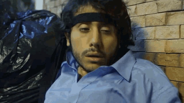 a man wearing a headband and a blue shirt is laying down