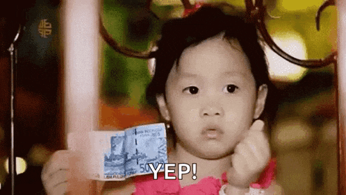 a little girl in a pink dress is holding a dollar bill and making a funny face .