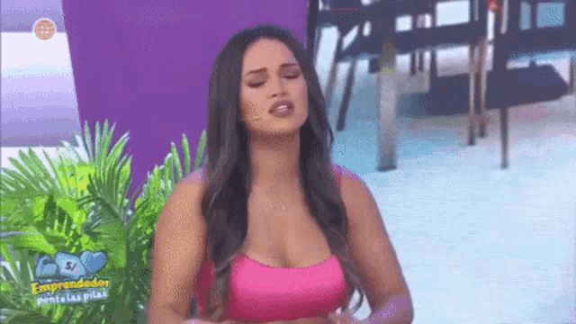 a woman in a pink crop top is standing in front of a purple wall .