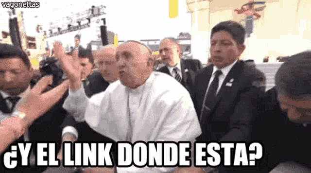 a man in a white robe is surrounded by men in suits and ties and says `` y el link donde esta ? ''