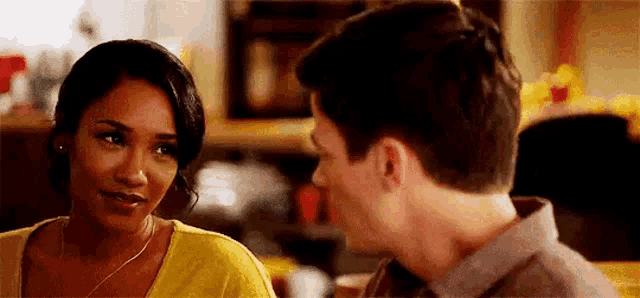 a man and a woman are looking at each other . the woman is wearing a yellow shirt .