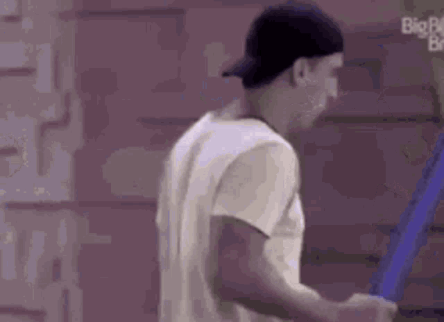 a man wearing a baseball cap and a white t-shirt is standing in front of a staircase .