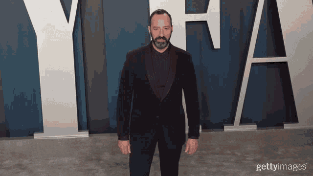 a man in a purple suit stands in front of a large y and a