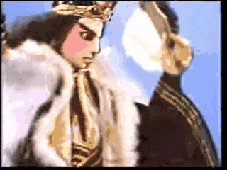 a man with a crown on his head stands next to a woman in a fur coat