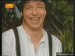 a man wearing a hat and suspenders is smiling and looking at the camera .