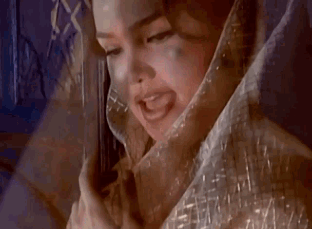 a close up of a woman 's face with a veil over her head .