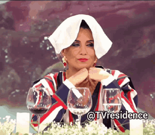 a woman with a towel wrapped around her head is sitting at a table with wine glasses